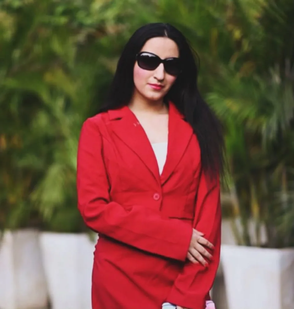 Sukoon Malhotra wearing a red suit and black sunglasses